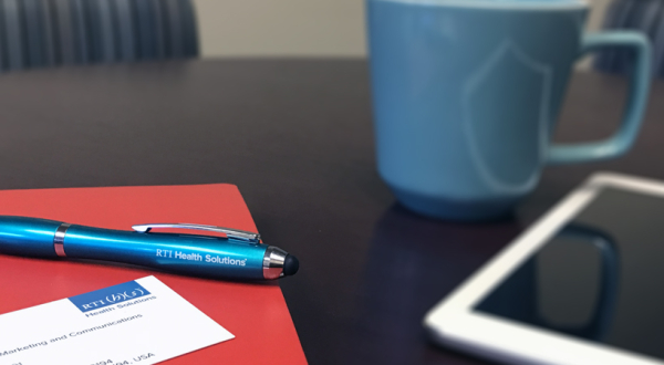 Folder and pen next to coffee and tablet